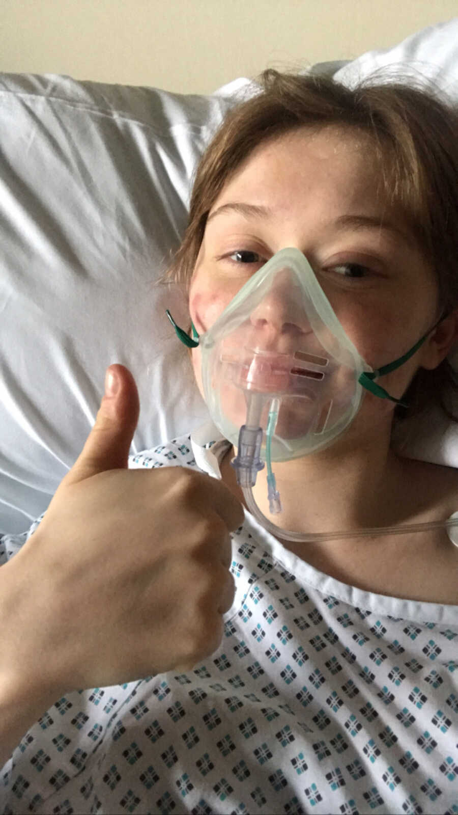 woman with endometriosis gives thumbs up with oxygen mask on