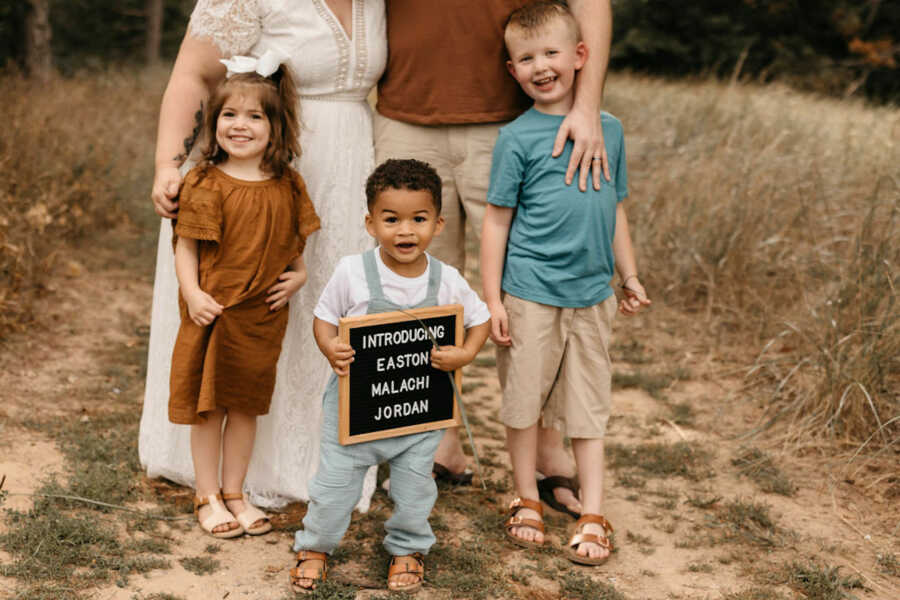 adoptive son holds sign announcing the finalized adoption with his siblings
