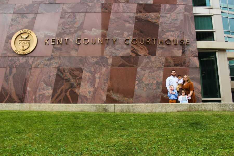 parents stand with their children outside courthouse after adoption