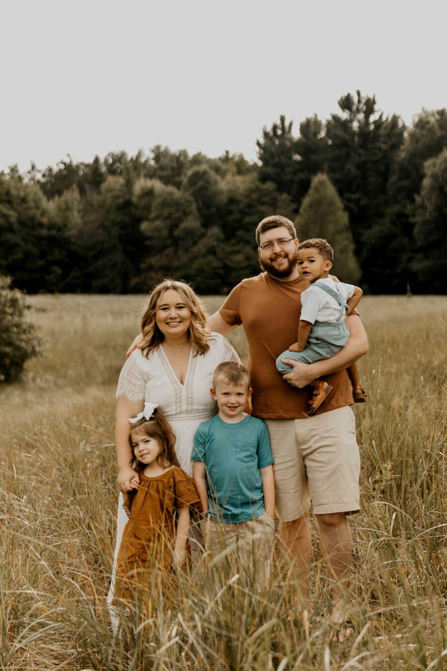 family of five through adoption stands in field together