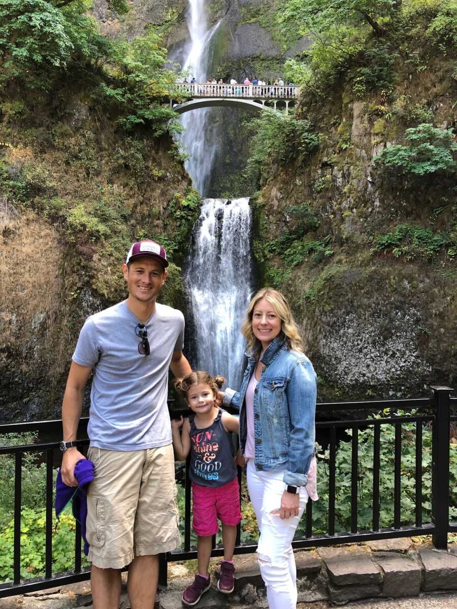 adoptive parents and daughter with waterfall in background 