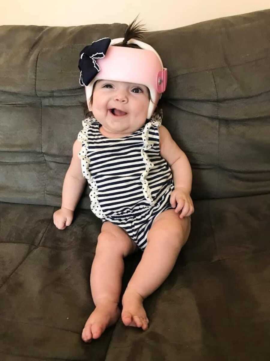 foster daughter sitting on couch with helmet on