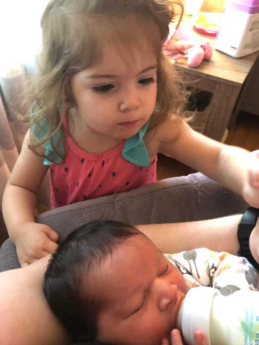 foster son with bottle while sister watches over