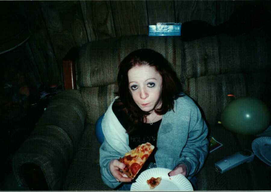 girl with Treacher Collins Syndrome sitting eating pizza
