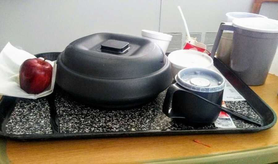 black plastic plate and cup on hospital tray with red apple