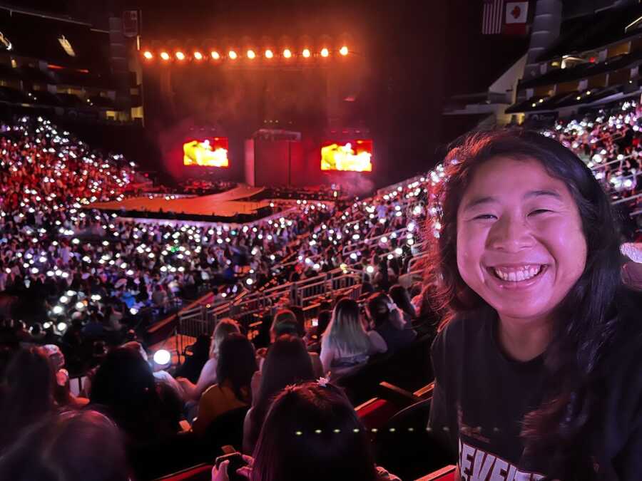 Korean adoptee at her seat smiling for a BTS concert