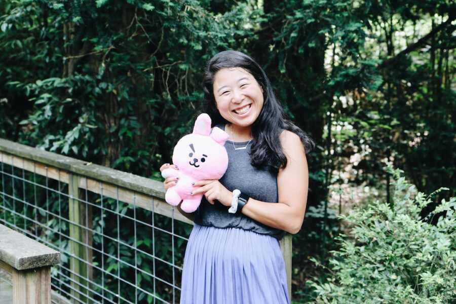 Korean adoptee holding a BTS plush animal