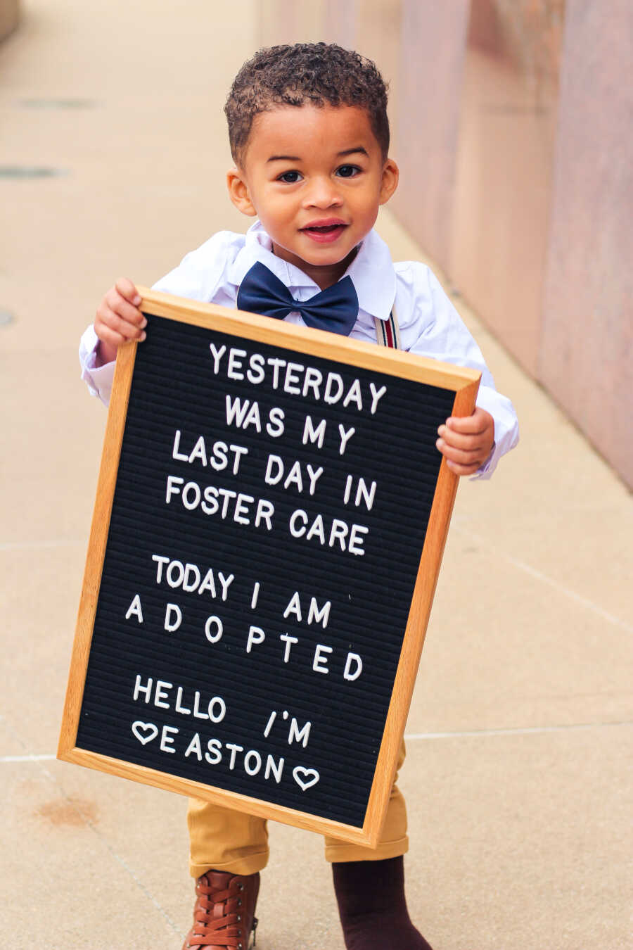 adoptive son holds sign announcing the finalized adoption