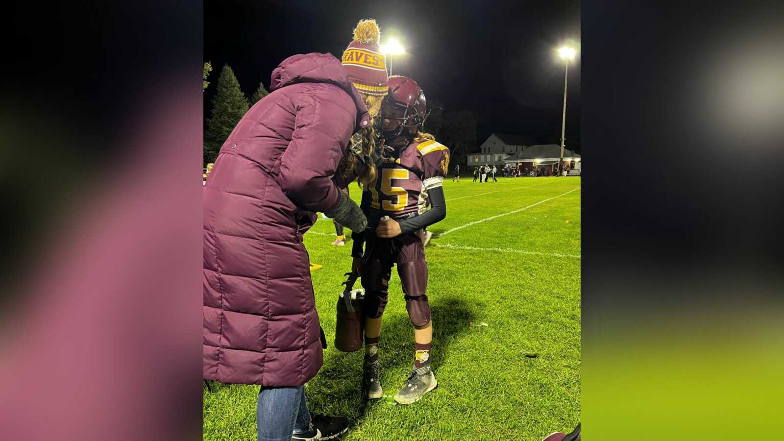 mom giving 11-year-old child who experiences anxiety pep talk during his football game