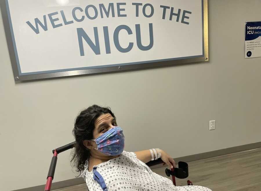 new mom in wheelchair in front of "welcome to the NICU" sign