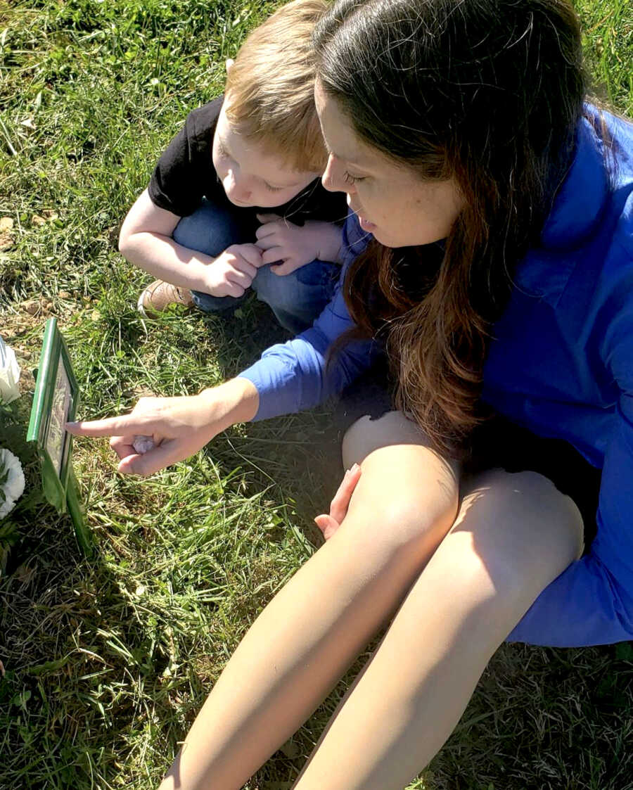 mother sitting her her child at her son's grave