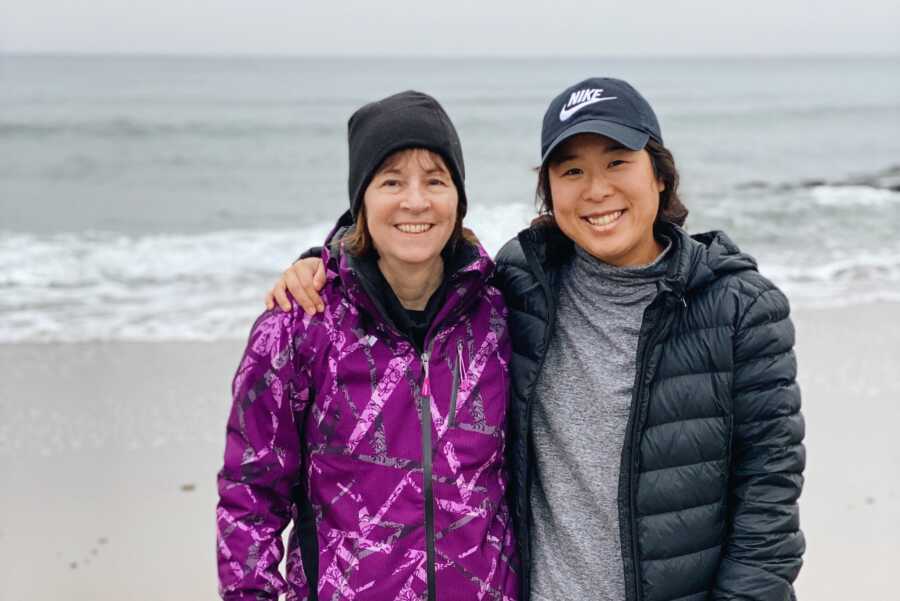 mom standing with korean adoptee daughter on the beach