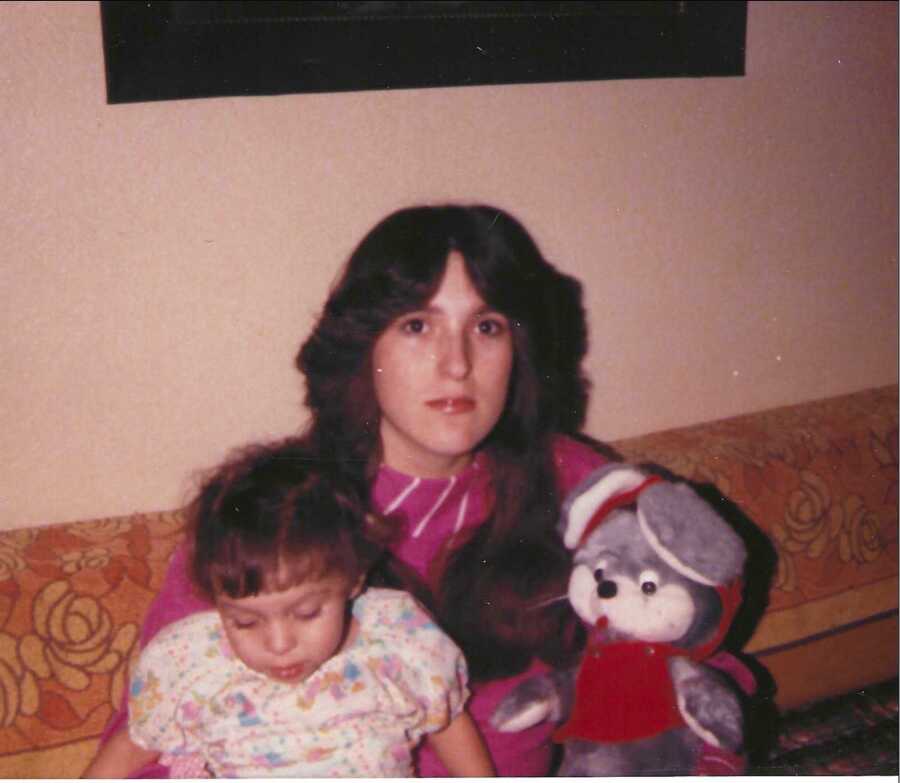 mom sitting on couch holding daughter and stuffed animal