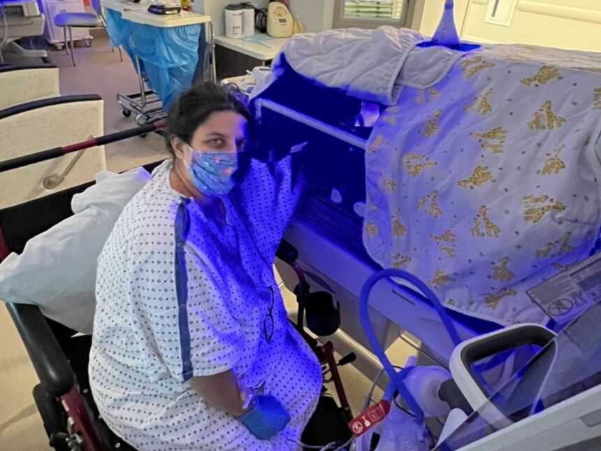 new mom sitting by her daughters bed in the NICU