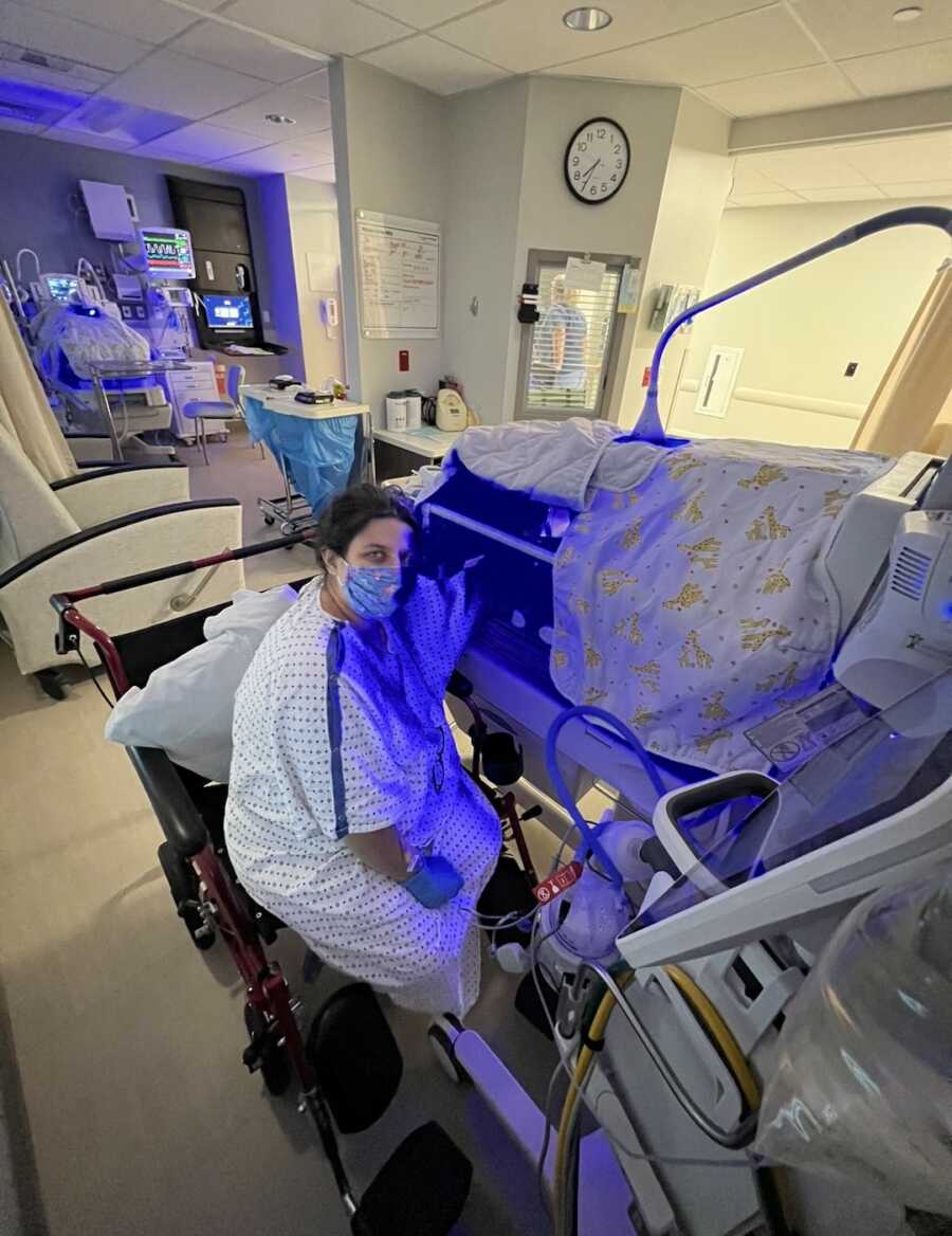 new mom sitting by her daughters bed in the NICU