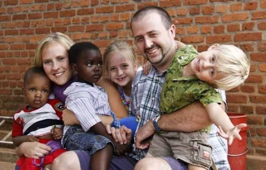 parents hold their two biological children and two adopted sons