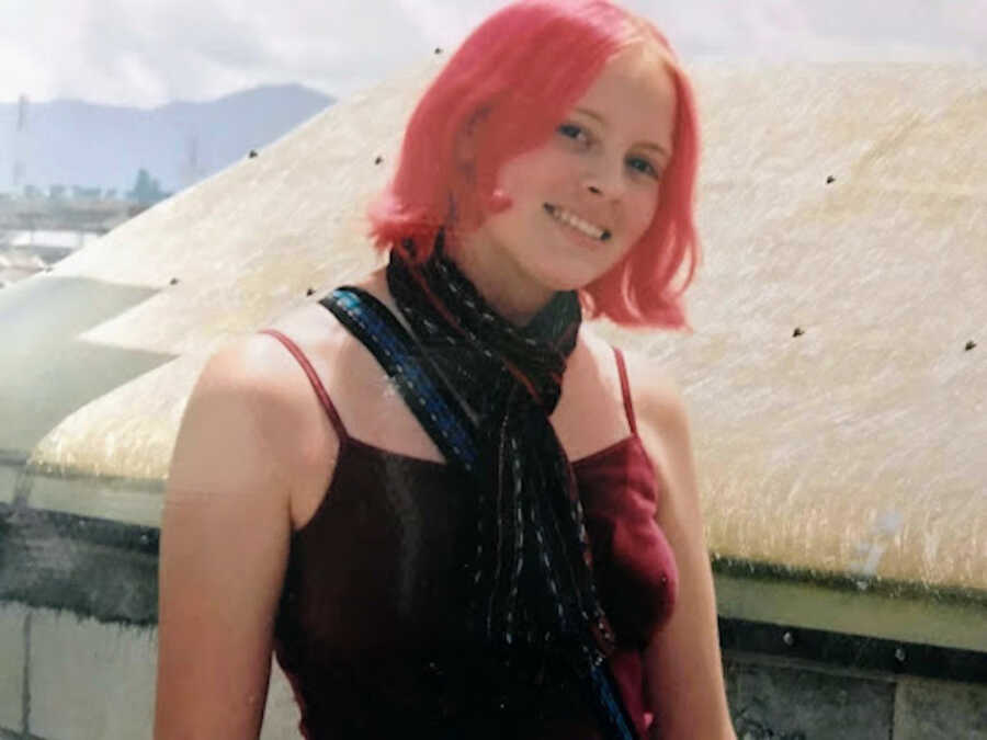 person wearing a scarf with pink hair smiling