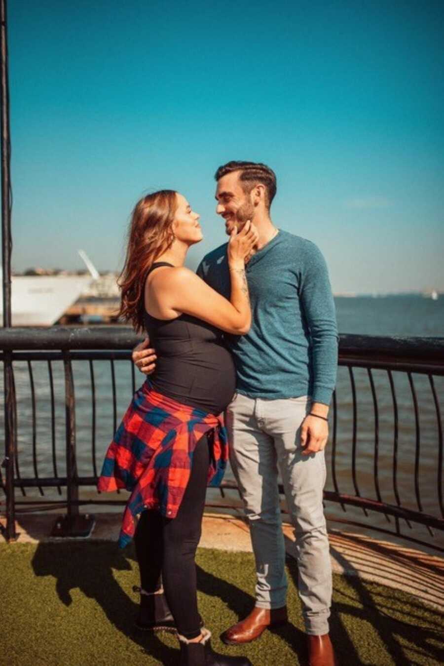 pregnant mom wearing all black holding husbands face