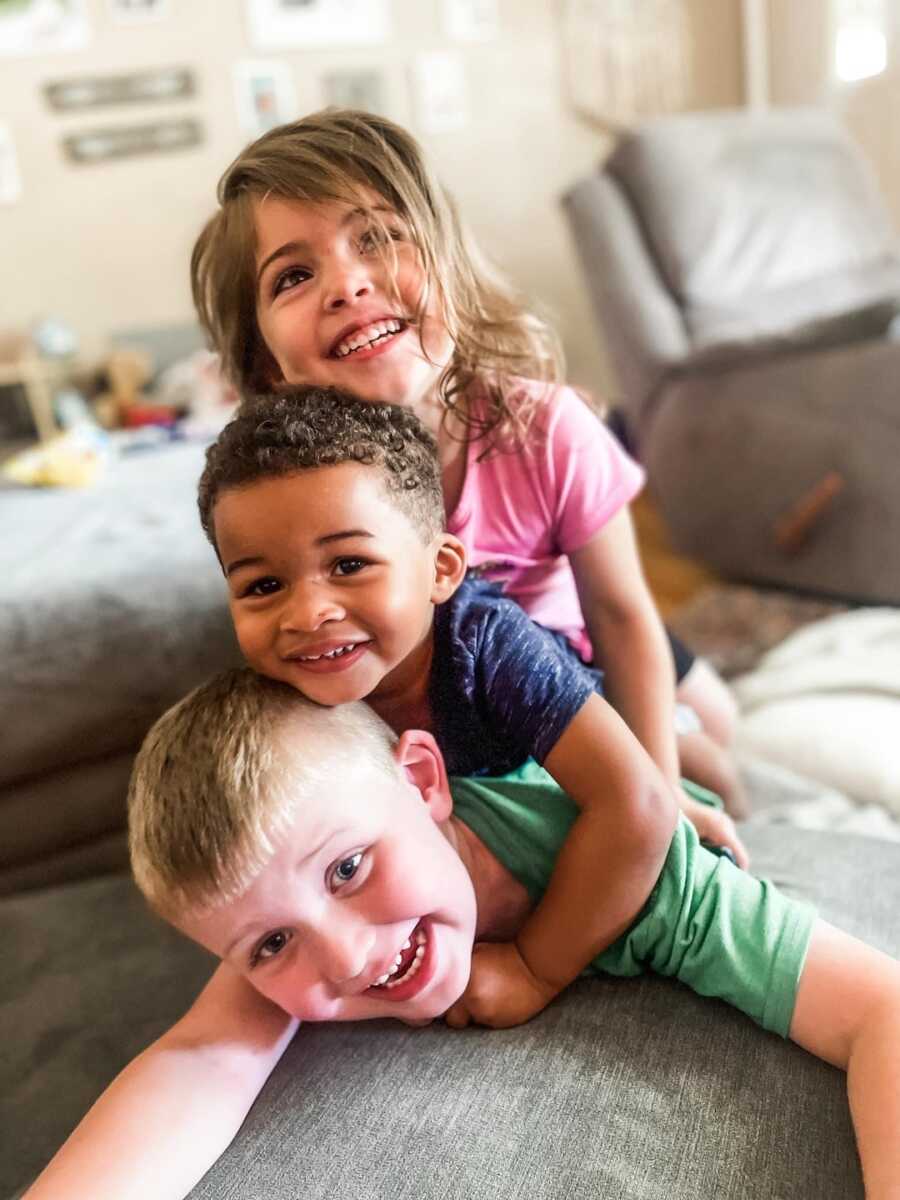 siblings lay on couch stacked on top of one another
