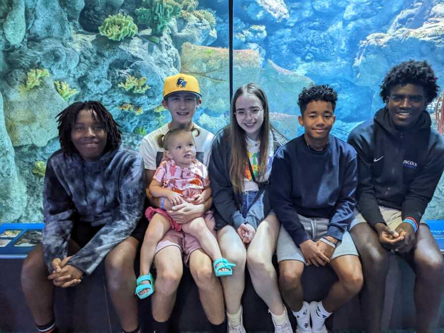 siblings sitting together on a ledge in-front of aquarium tank