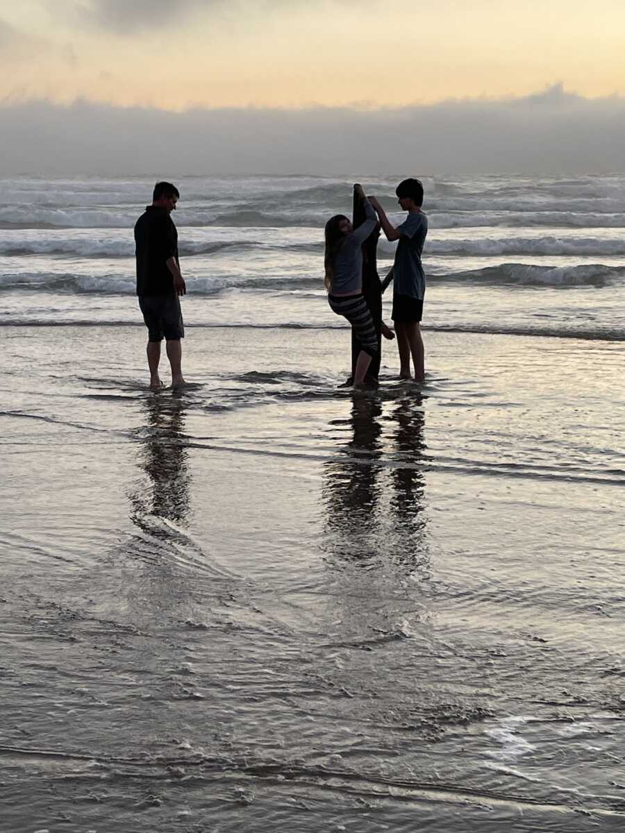 dad with his two children standing out in the water at the beach
