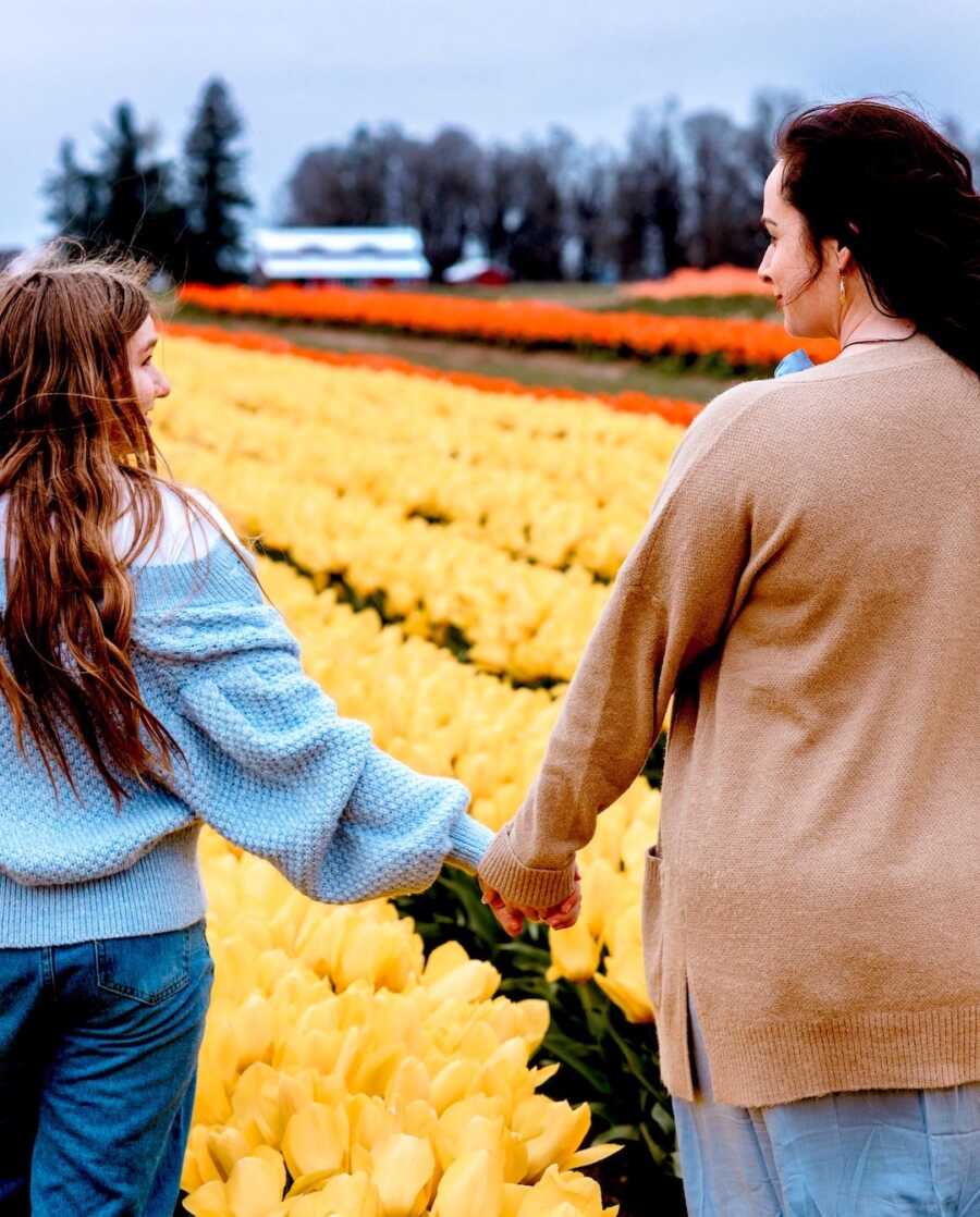 stepmom holding her stepdaughters hand while in a tulip field