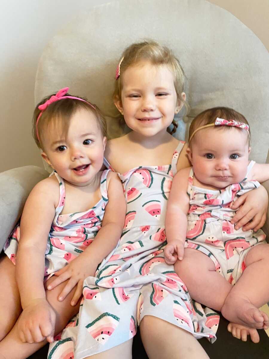 three sisters, two biological one foster, sitting on chair together