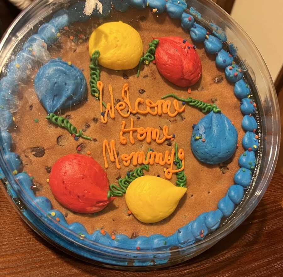 cookie cake with "welcome home mommy" written on it