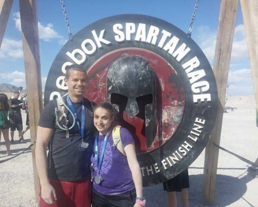 woman with asthma stands with man in front of spartan race sign