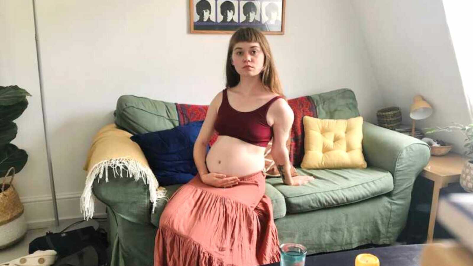 woman with endometriosis sits on couch holding stomach