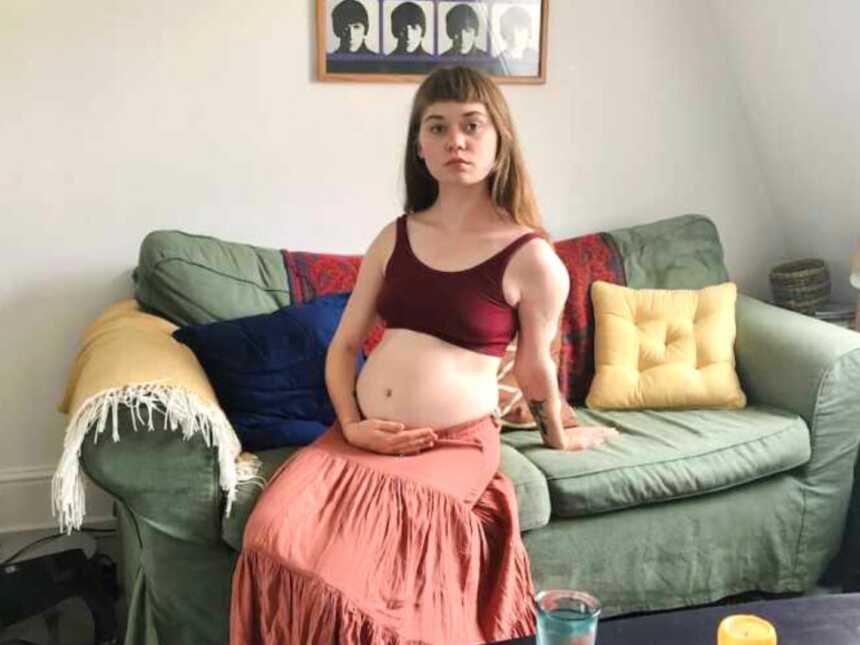 woman with endometriosis sits on couch holding stomach