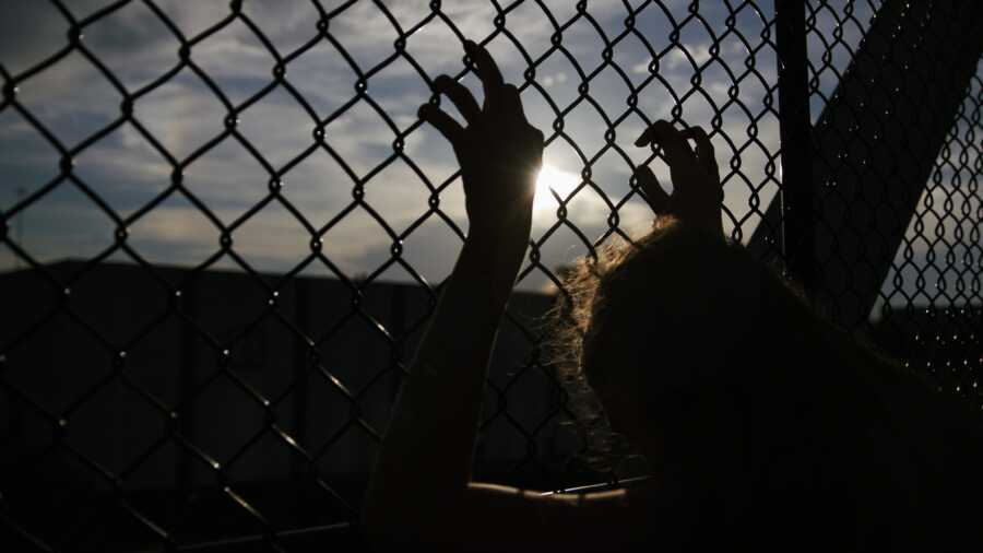 woman gripping fence with fingers