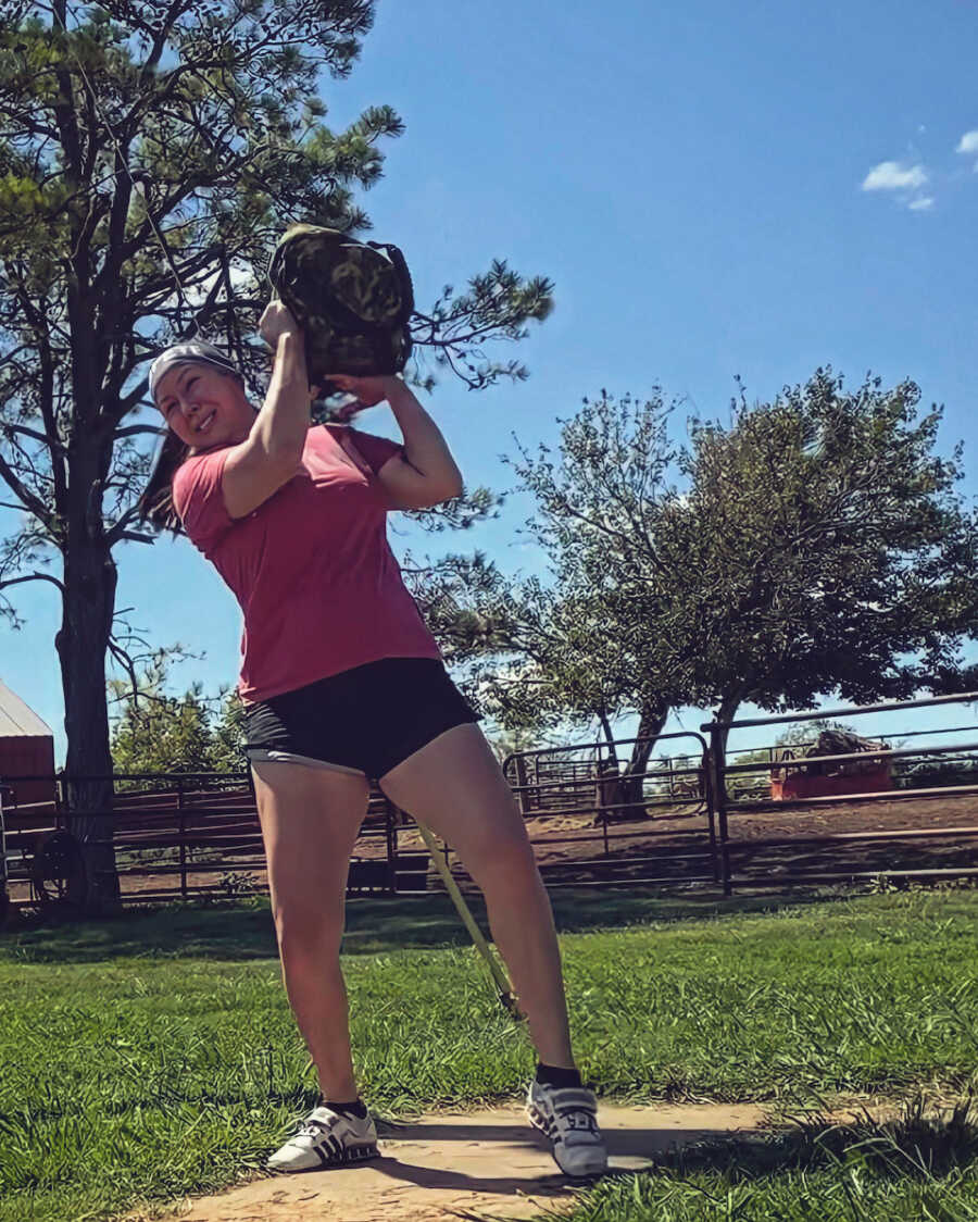 woman lifting weight up to shoulder outside