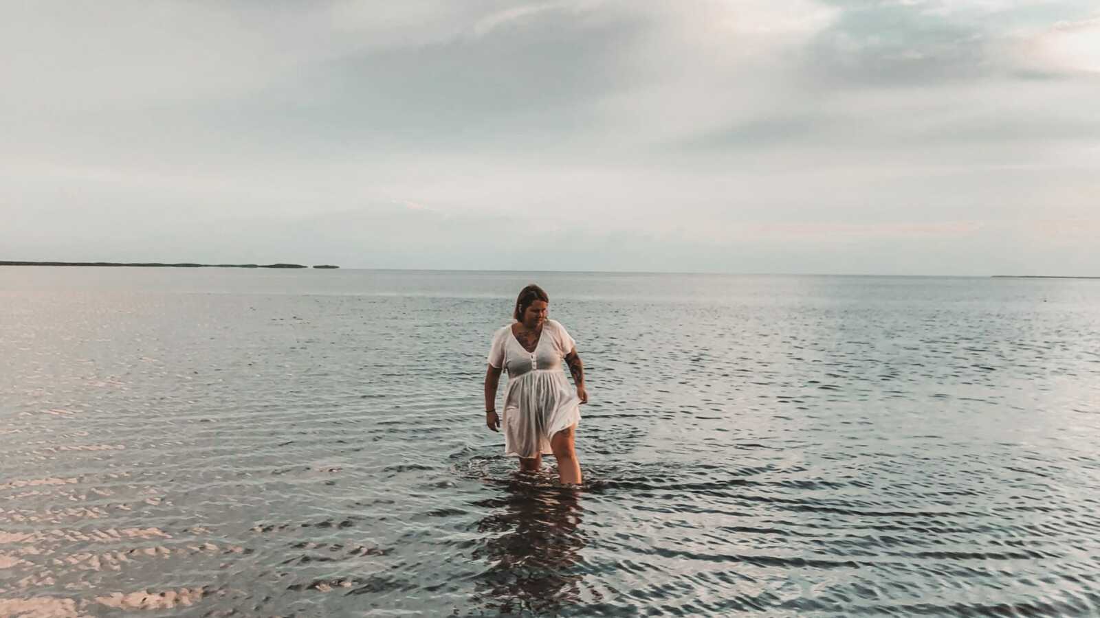 woman in white dress walks through shallow water