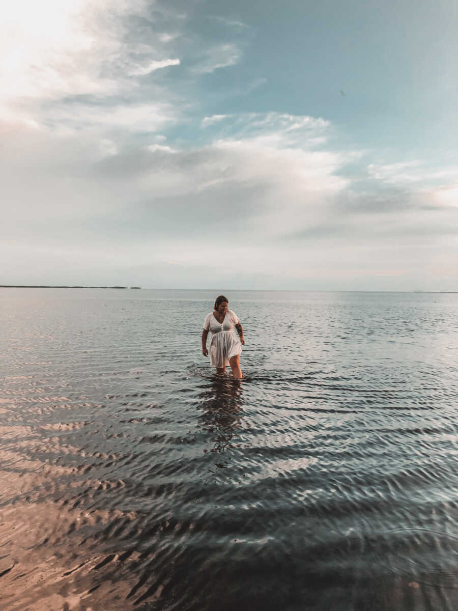 woman in white dress walks through shallow water