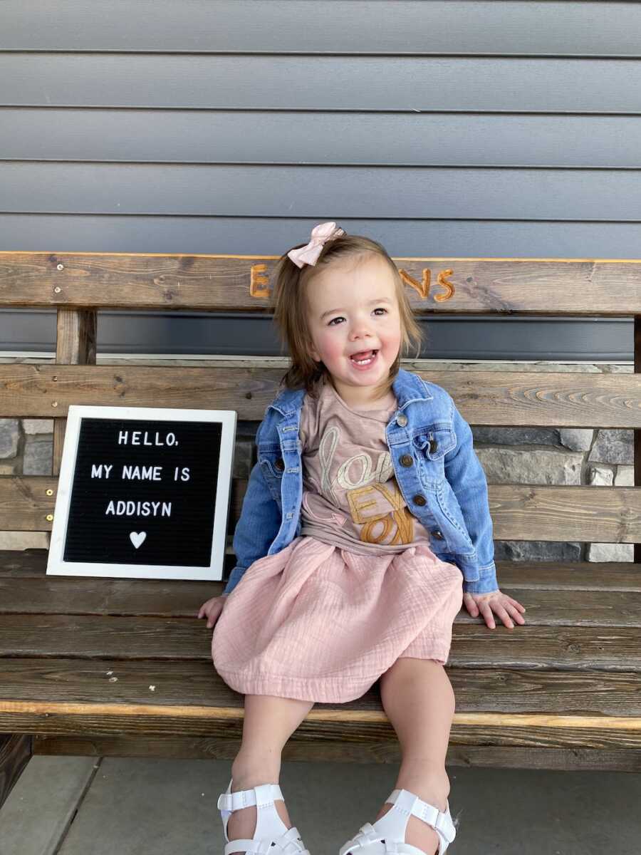 young girl on her adoption day sitting on bench