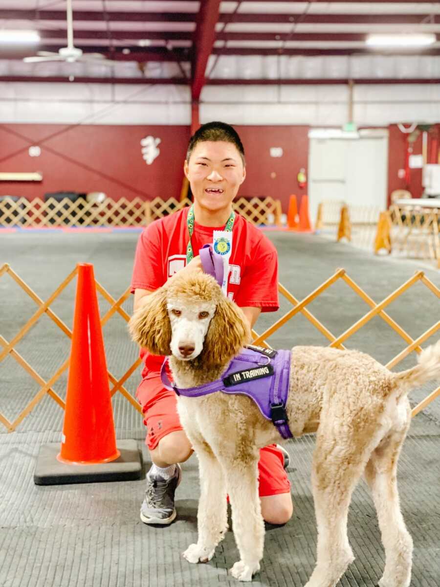 Sobreviviente de FASD en camisa roja con perro de servicio de caniche