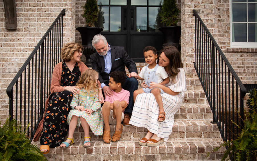 grandparents and mother with foster and adopted siblings sitting on brick steps