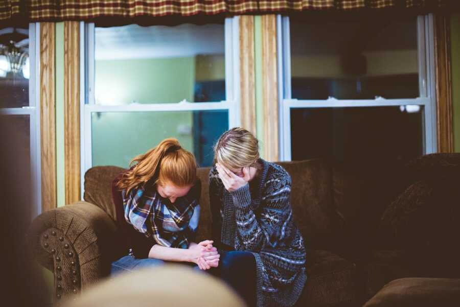 friends supporting one another through grief while sitting on couch