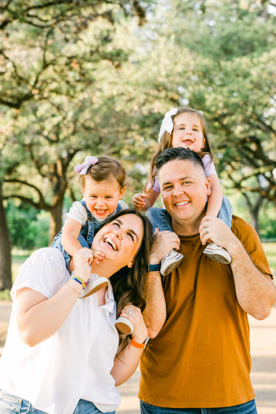 Mom and dad hold their daughters on their shoulders 