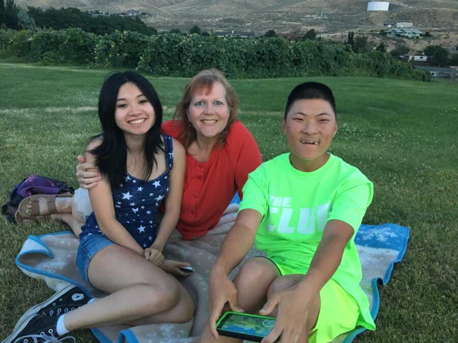 Mom with FASD son and daughter sitting on blanket outside