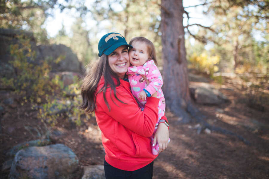 Mom holds her special needs daughter in a forest 